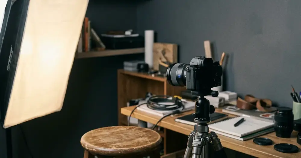 Câmera em tripé apontada para uma banqueta em estúdio caseiro com softbox aceso